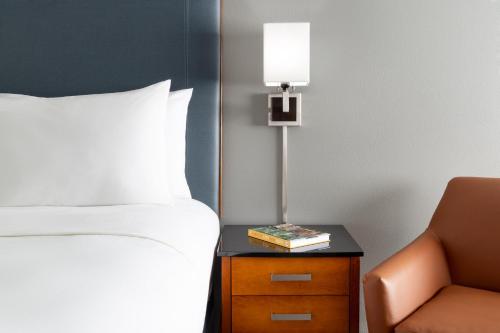 a bedroom with a bed and a lamp and a chair at Courtyard Montvale in Montvale