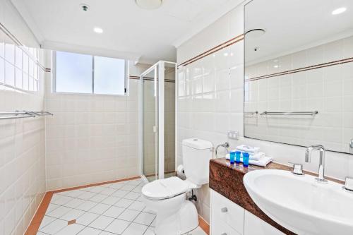 a white bathroom with a toilet and a sink at Oscar on Main 2B - Heart of Main Beach Ocean Views - Hosted by Coastal Letting Co. in Gold Coast