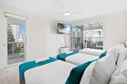 a white room with two beds and a tv at Oscar on Main 2B - Heart of Main Beach Ocean Views - Hosted by Coastal Letting Co. in Gold Coast