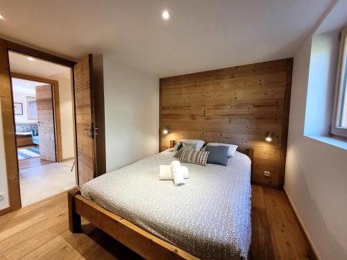 - une chambre avec un lit et un mur en bois dans l'établissement Résidence Ambrocella - Très bel appartement, lumineux, bel espace de vie MAE-0781, aux Gets