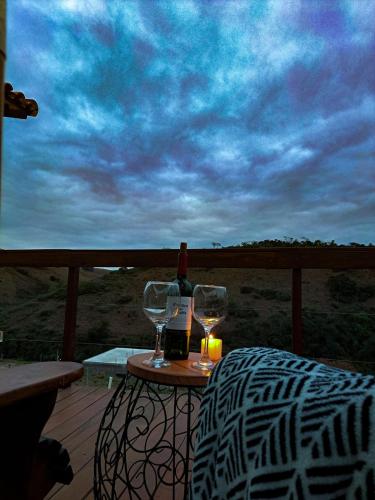 a table with two wine glasses on a deck at Aconchego do Pôr do Sol Sebollas in Inconfidência