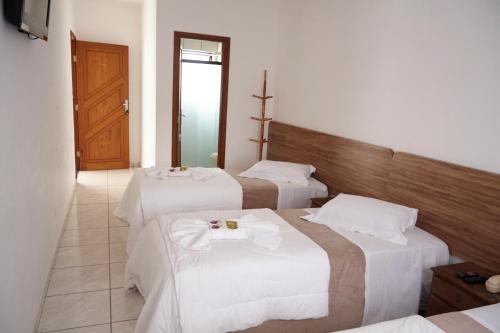 a hotel room with two beds and a door at Pousada das Estrelas in São Thomé das Letras