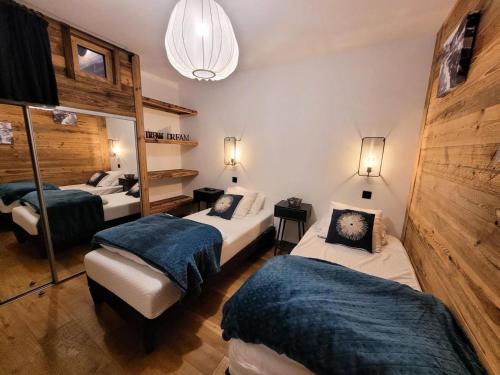 une chambre avec trois lits et un miroir dans l'établissement Résidence Grand Theatre - Appartement duplex d'exception, belle exposition, au calme MAE-0881, aux Gets