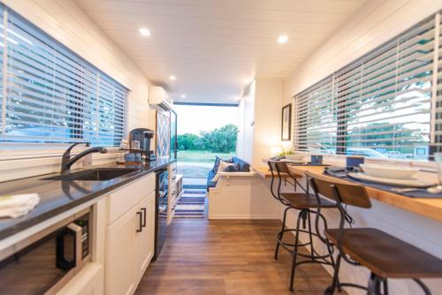 BellmeadThe Bluebonnet-Tiny Container Home Country Setting 12 min to Downtown的厨房设有2个吧台凳和带窗户的柜台。
