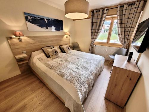 une chambre avec un grand lit et une fenêtre dans l'établissement Résidence Le Vorzay - Appartement Esprit Montagne MAE-0811, aux Gets