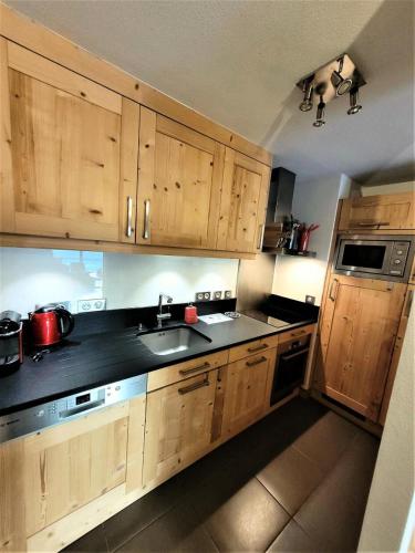 une cuisine avec des armoires en bois et un évier dans l'établissement Résidence Mont Chery - T4 dans prestigieuse résidence au pied des pistes MAE-0891, aux Gets