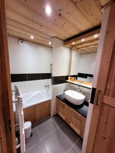 une salle de bain avec une baignoire et un lavabo et une baignoire dans l'établissement Résidence Mont Chery - T4 dans prestigieuse résidence au pied des pistes MAE-0891, aux Gets