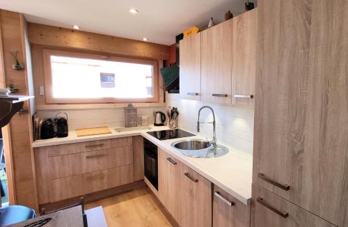 une cuisine avec des armoires en bois, un évier et une fenêtre dans l'établissement Résidence Le Vorzay - Appartement Esprit Montagne MAE-0811, aux Gets