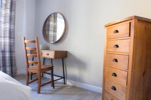 a bedroom with a dresser and a chair and a mirror at Boutique Home from Home in London