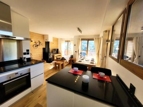 une cuisine et un salon avec une table et des serviettes rouges dans l'établissement Résidence Le Kilimandjaro - Appartement lumineux avec vue sur le domaine des Chavannes MAE-1081, aux Gets
