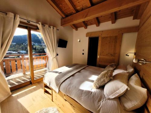 un grand lit dans une chambre avec une grande fenêtre dans l'établissement Résidence Le Kilimandjaro - Appartement lumineux avec vue sur le domaine des Chavannes MAE-1081, aux Gets