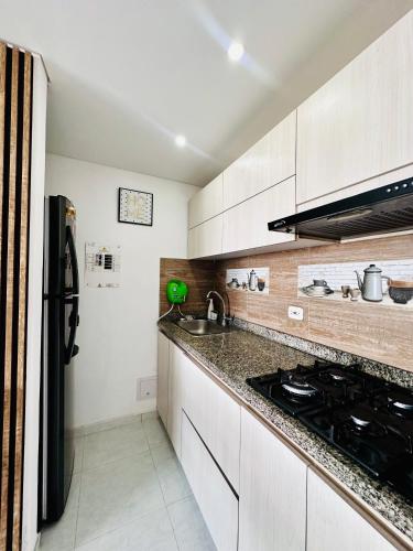a kitchen with white cabinets and a sink and a stove at Apartamento tranquilo y completo a 5 min de Girardot, cerca al Centro Comercial Peñaliza Mall in Ricaurte