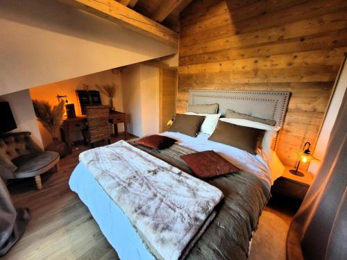 une chambre avec un grand lit avec un mur en bois dans l'établissement Résidence Le Hameau Des Cornuts - Vivez un séjour de charme dans cet appartement sous toit MAE-1021, aux Gets