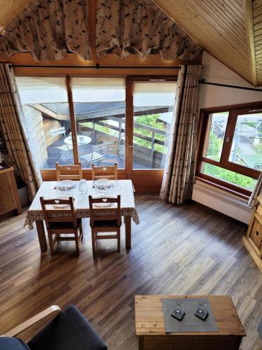 une salle à manger avec une table, des chaises et des fenêtres dans l'établissement Résidence La Bouillandire - Appartement lumineux avec vue imprenable MAE-1121, aux Gets