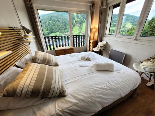 un grand lit dans une chambre avec une grande fenêtre dans l'établissement Résidence Grizzly - Appartement skis aux pieds, entièrement rénové MAE-1051, aux Gets