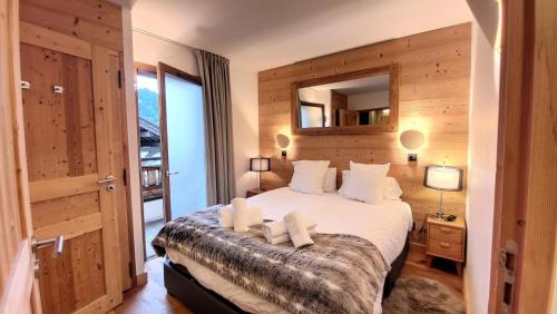 une chambre avec un grand lit et un miroir dans l'établissement Résidence Le Kilimandjaro - Appartement très cosy, 2 chambres en suite, proche commerces MAE-1201, aux Gets
