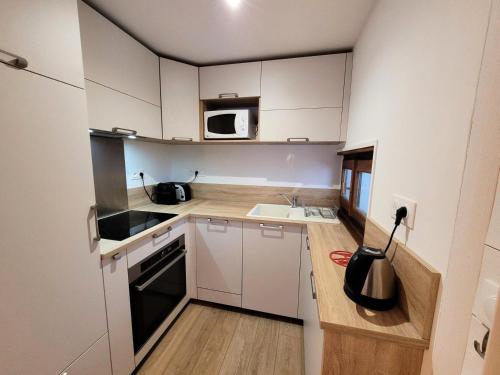 une petite cuisine avec des armoires blanches et un micro-ondes dans l'établissement Résidence Helios - Bel appartement rénové, au calme et proche du centre MAE-1251, aux Gets