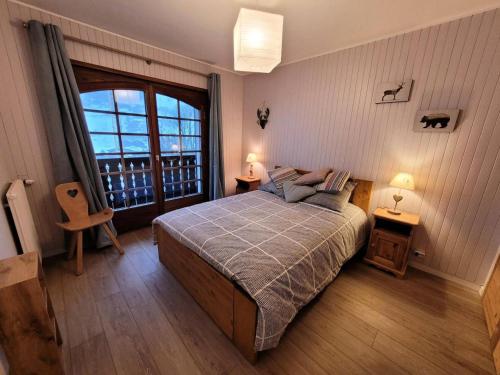 une chambre avec un lit et une grande fenêtre dans l'établissement Résidence Helios - Bel appartement rénové, au calme et proche du centre MAE-1251, aux Gets