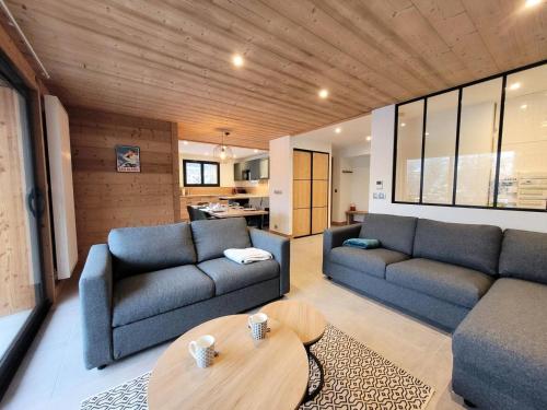 un salon avec deux canapés bleus et une table dans l'établissement Résidence Le Nantaux - Appartement lumineux, dans un chalet entièrement rénové, centre station MAE-0931, aux Gets