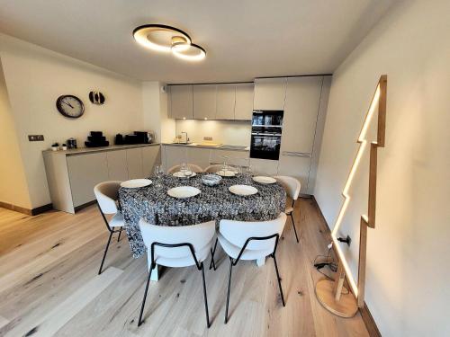 une table de salle à manger avec des chaises et une cuisine dans l'établissement Résidence Le Stella - Appartement haut de gamme 6 personnes au centre MAE-1001, aux Gets