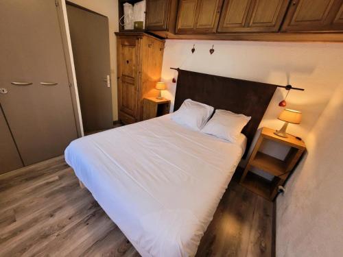 - une chambre avec un lit avec des draps blancs et 2 lampes dans l'établissement Résidence Eden Roc I - Appartement lumineux et bien agencé, plein centre MAE-1291, aux Gets