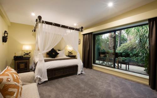 a bedroom with a canopy bed and a large window at Jamala Wildlife Lodge in Canberra