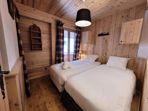 deux lits dans une chambre aux murs en bois dans l'établissement Résidence Eden Roc Ii - T3 centre station et proche des pistes de ski MAE-1271, aux Gets