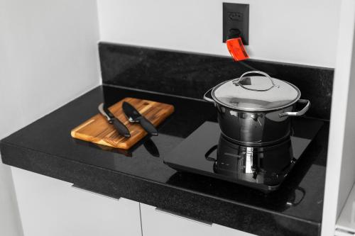 a pot on a stove with a wooden cutting board at Alta Garden Housi João Pessoa by Carpediem in João Pessoa