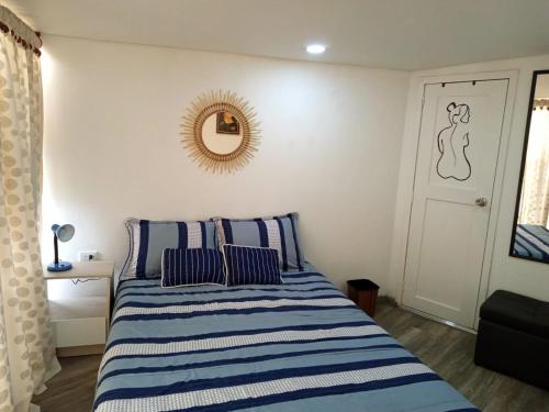 a bedroom with a bed with blue and white stripes at Hostal CasAlé Usaquén in Bogotá