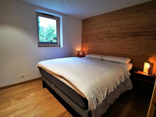 une chambre avec un grand lit avec un mur en bois dans l'établissement Résidence Ambrocella - Bel appartement lumineux, exposition Sud ouest MAE-1281, aux Gets