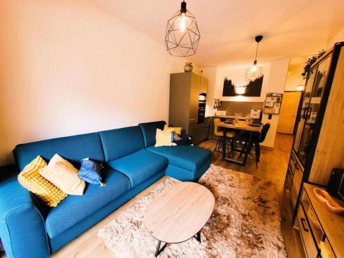 un salon avec un canapé bleu et une table dans l'établissement Résidence Le Stella - Appartement 4 personnes au centre MAE-1331, aux Gets