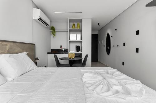 a bedroom with a large white bed and a table at Alta Garden Housi João Pessoa by Carpediem in João Pessoa