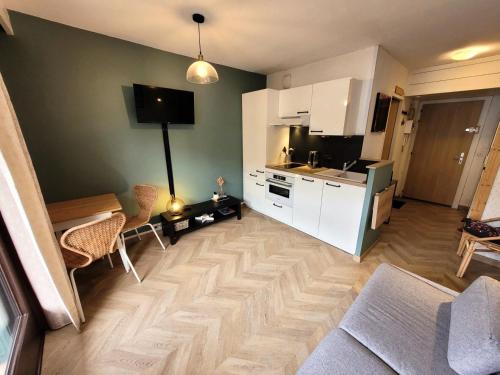 une cuisine avec des armoires blanches et un salon dans l'établissement Résidence Ranfolly - Studio lumineux et cosy au cœur du village MAE-1361, aux Gets