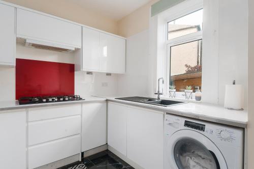 a white kitchen with a washing machine and a window at 2 Bed Property, sleeps 5, free parking, near city centre in Edinburgh