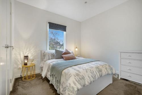 a white bedroom with a bed and a window at Blue Chip Williamstown Beach Bay Townhouse in Williamstown