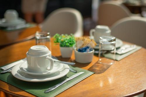 a wooden table with a white cup and plates on it at Pousada Santa Felicidade in Campos do Jordão