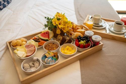 a tray of breakfast foods on a bed at Pousada Santa Felicidade in Campos do Jordão