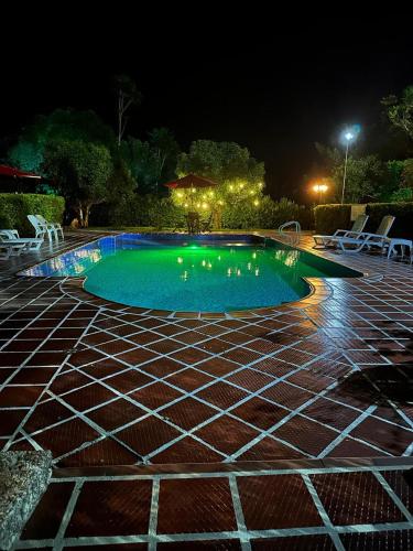 a swimming pool at night with chairs around it at El Ensueño Ecohostal & Glamping in Mocoa