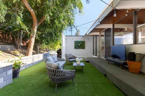 a patio with chairs and a tv on the grass at Mid-century Masterpiece With Pool , Spa & Bbq in Escondido