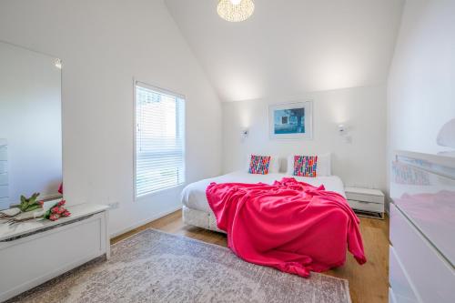 Un dormitorio con una cama con una manta roja encima. en Palm Beach Penthouse by Waiheke Pure, en Palm Beach