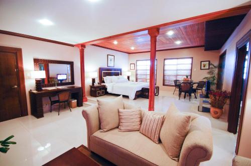 a living room with a couch and a bedroom at Citystate Asturias Hotel Palawan in Puerto Princesa City