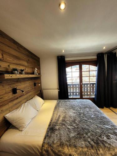 une chambre avec un grand lit avec un mur en bois dans l'établissement Résidence Helios - Appartement 2 chambres - vue splendide MAE-1111, aux Gets