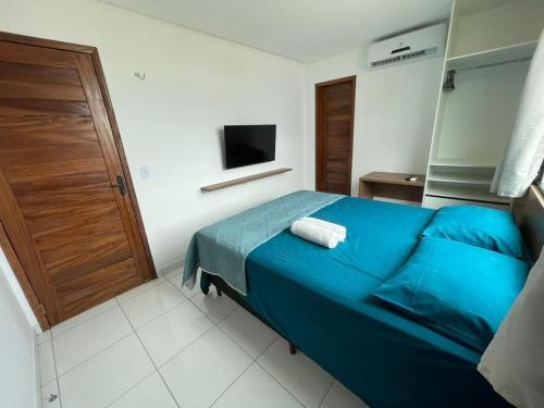 ein Schlafzimmer mit einem blauen Bett und einem TV in der Unterkunft Chalé Paraíso, Chaleville Maramar - Conforto, segurança, internet e Jacuzzi Vista mar in Luis Correia