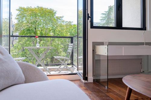 Cette chambre dispose d'un canapé et d'un balcon avec une table. dans l'établissement Trendy ,quit and chic, à Paris