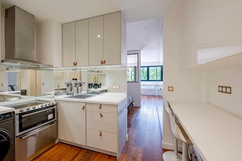 une grande cuisine avec des placards blancs et un évier dans l'établissement Trendy ,quit and chic, à Paris