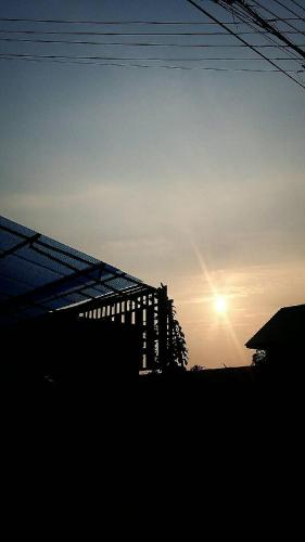a building with the sun setting in the background at Lampang Lanna Home in Lampang