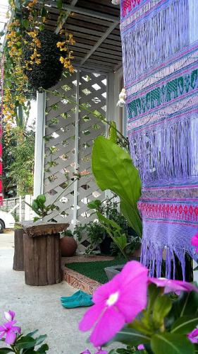 a purple vase with flowers in front of a building at Lampang Lanna Home in Lampang