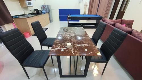 a dining room table with four chairs and a couch at Family Pool Villa Chaam in Cha Am