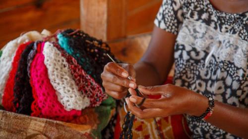 a woman is knitting a hat on a table at Hotel Galería La Vieja Sara in Ríohacha