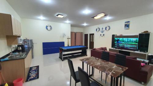 a living room with a couch and a table and a television at Family Pool Villa Chaam in Cha Am